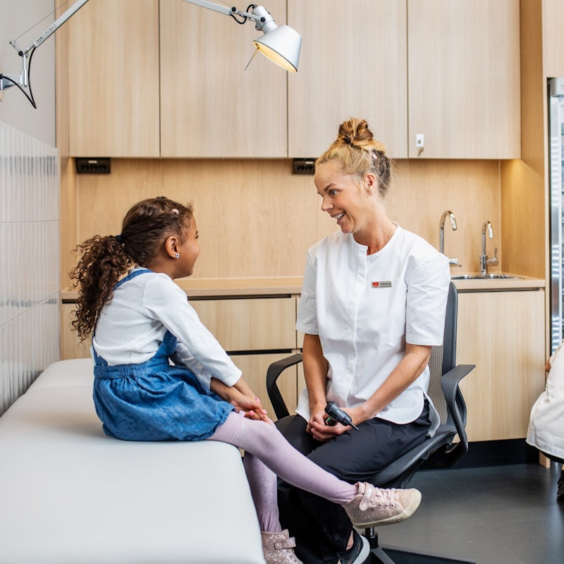 Nurse smiling at child whilst another takes something from the fridge