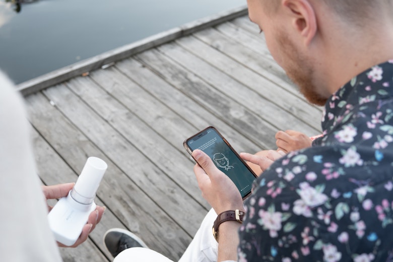 Two People Using AsthmaTuner Outside On A Dock