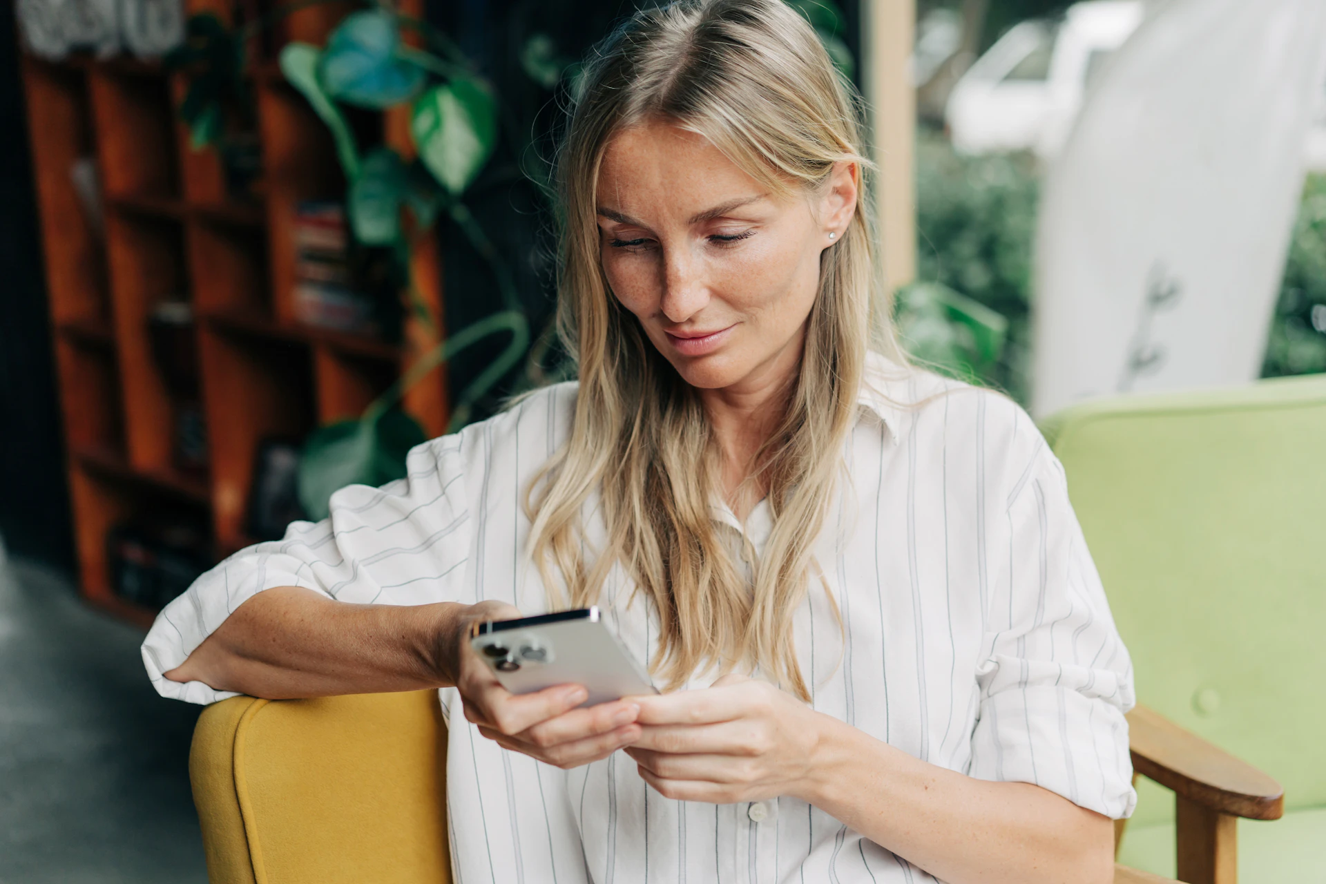 En kvinna som sitter och använder sin mobil för att konakta Min Doktor