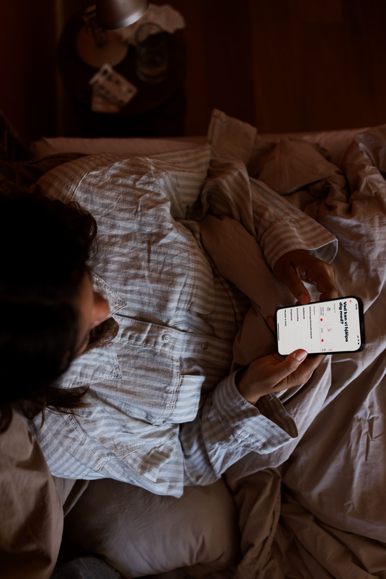 kvinna söker vård i sängen via mobilen