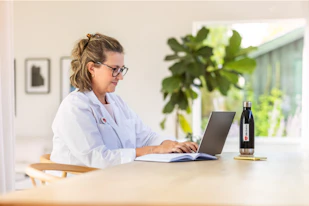 Bild på en kvinnlig läkare som använder sin bärbara dator vid ett skrivbord