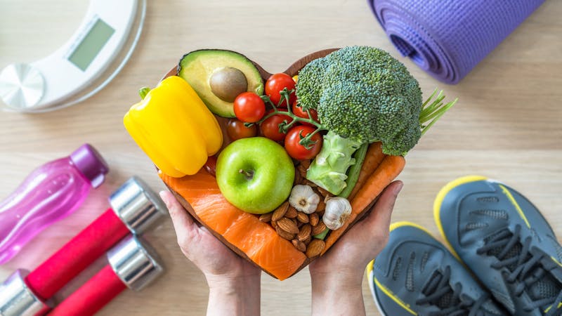 Woman holding a plate of food with exercise equipment on the floor in the background