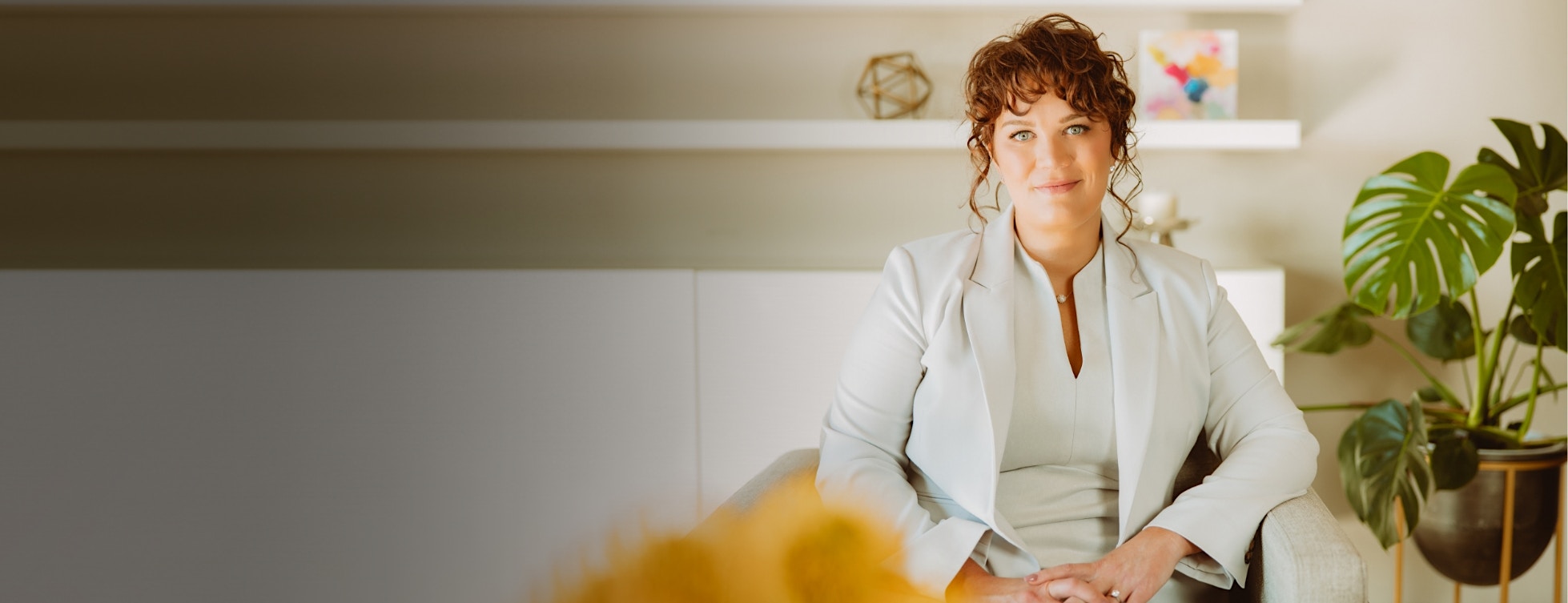 Seated model in white with red hair looking at camera.