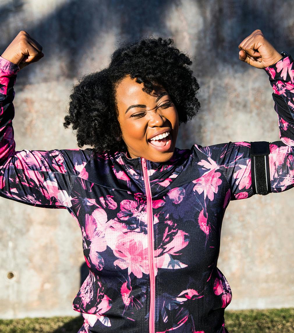 Woman in a pink and black jacket flexing her biceps