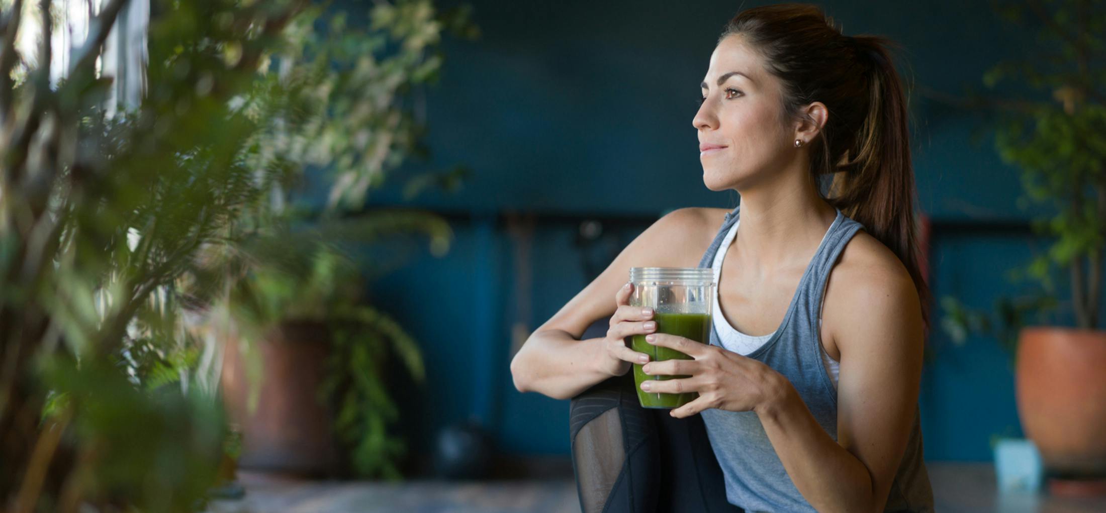 Woman sitting drinking a green juice