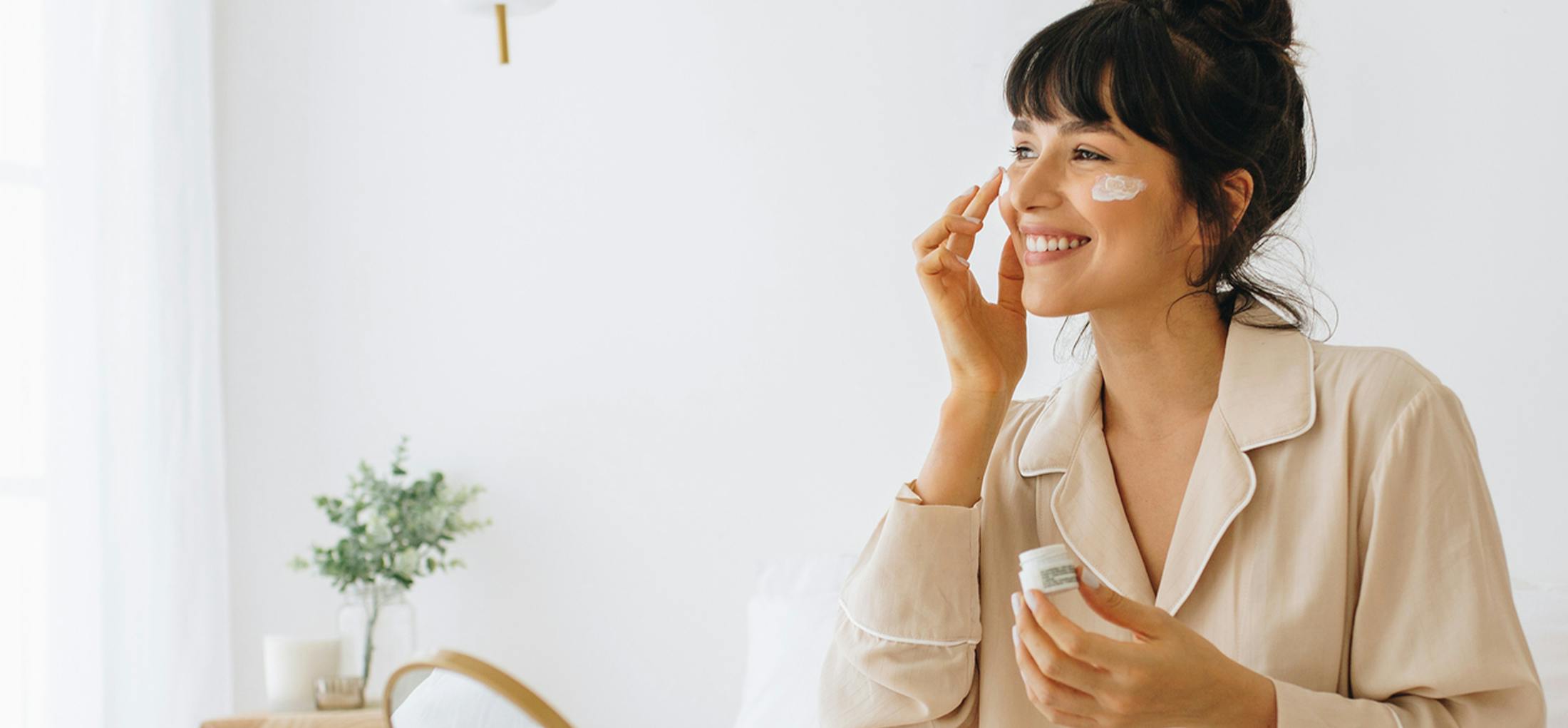 Woman putting lotion on her cheeks