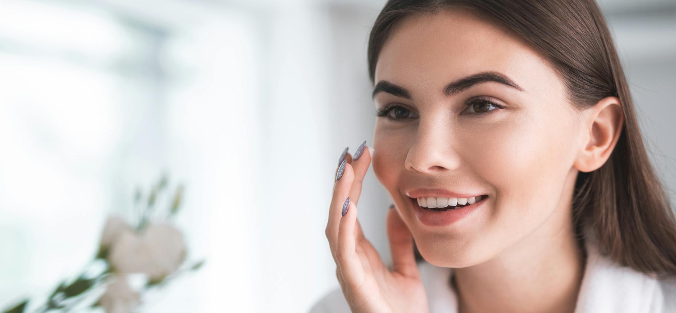 Woman putting lotion on her cheek