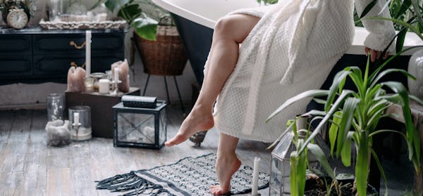 Womans legs as she sits on the edge of a bath tub