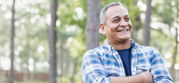 Man standing out in the woods with his arms crossed