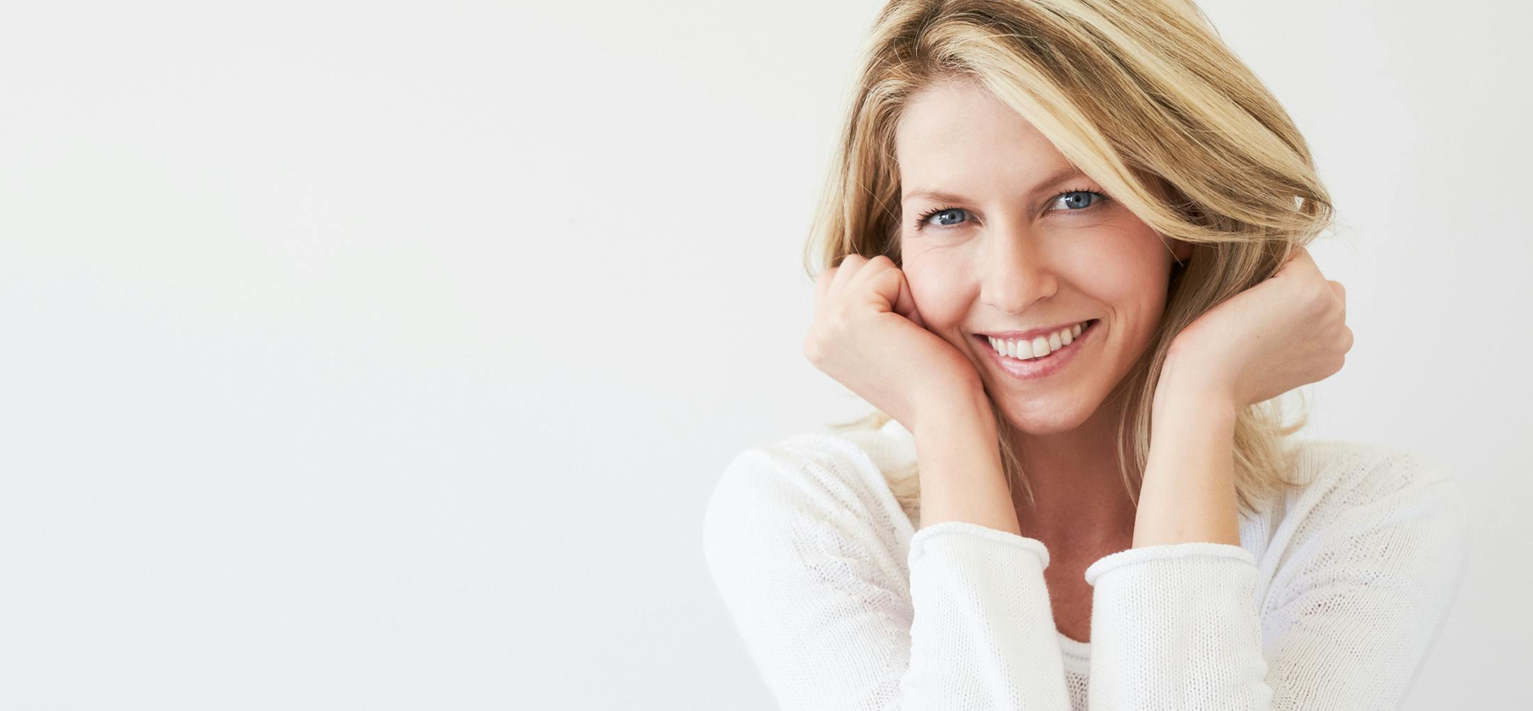 Woman in a white top with her hands on her cheeks