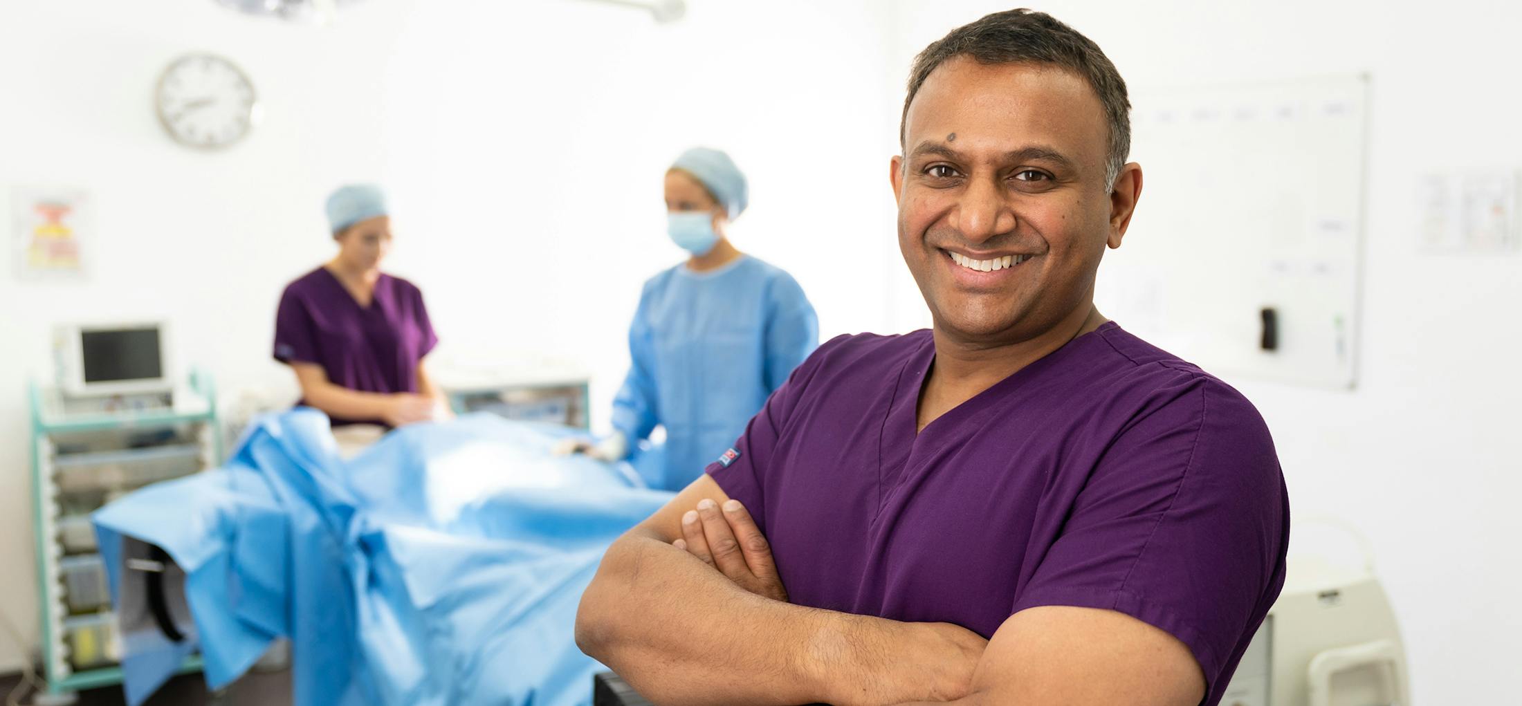 Doctor standing in an operating room with his arms crossed
