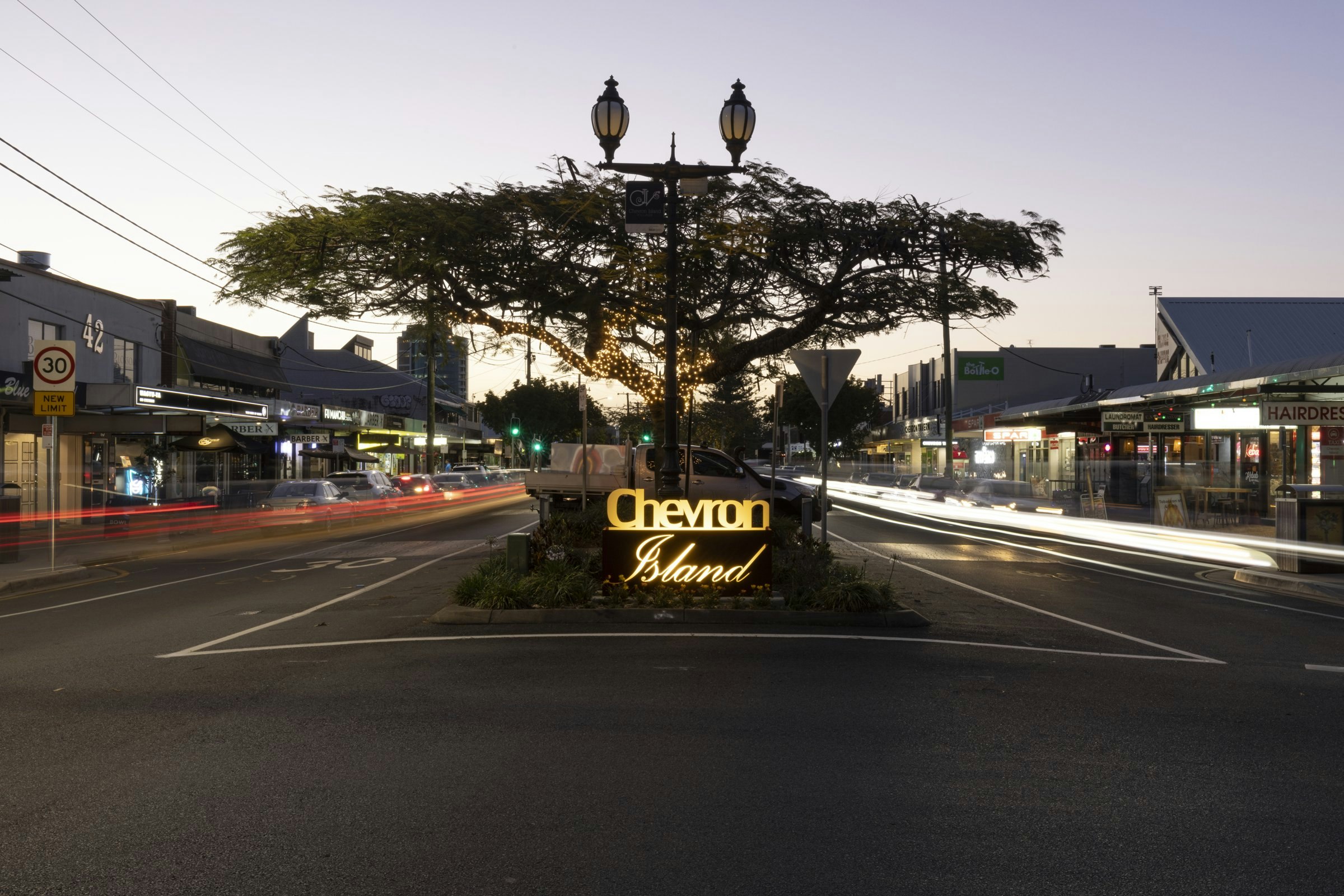 The Chevron Island sign under the big tree on Thomas Drive at dusk