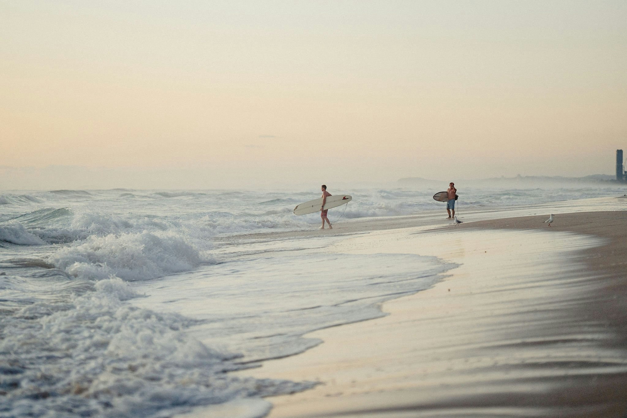 Surfers walking out at first light on Northcliffe beach, Surfers Paradise