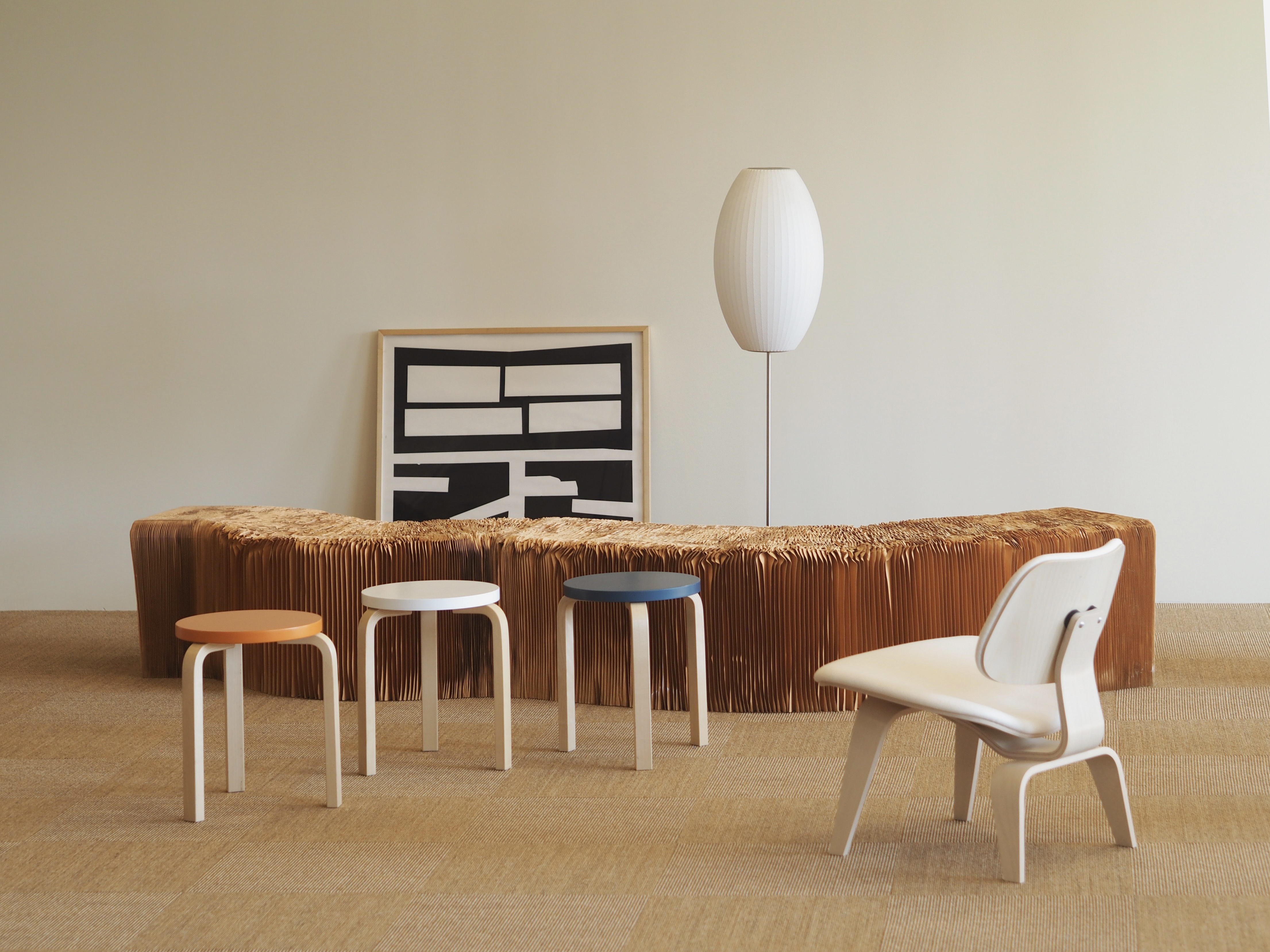 Photo of the Notion office, including three stools and a white chair. There is a floor lamp and a black and white abstract painting in the background.