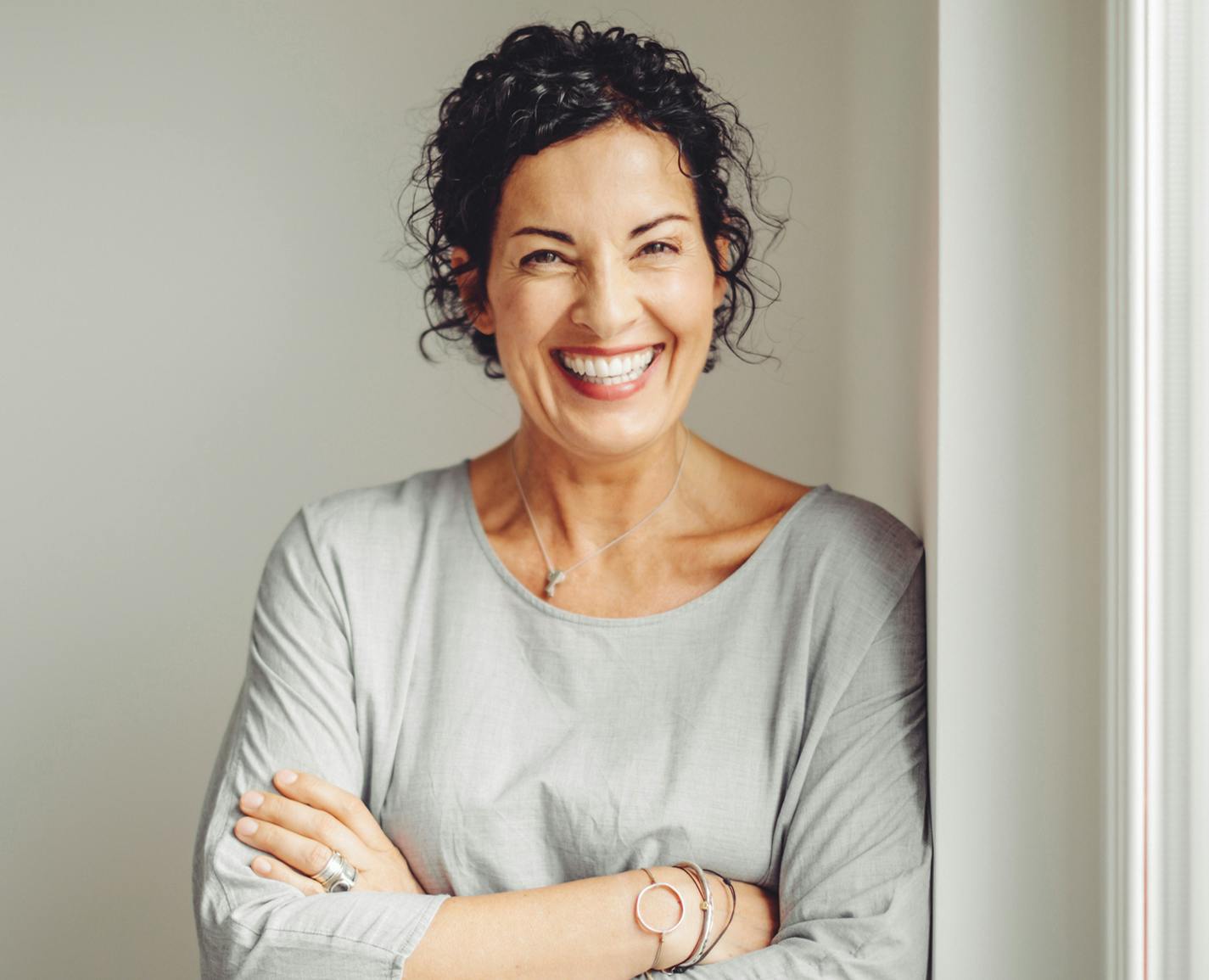 woman smiling and leaning on a wall