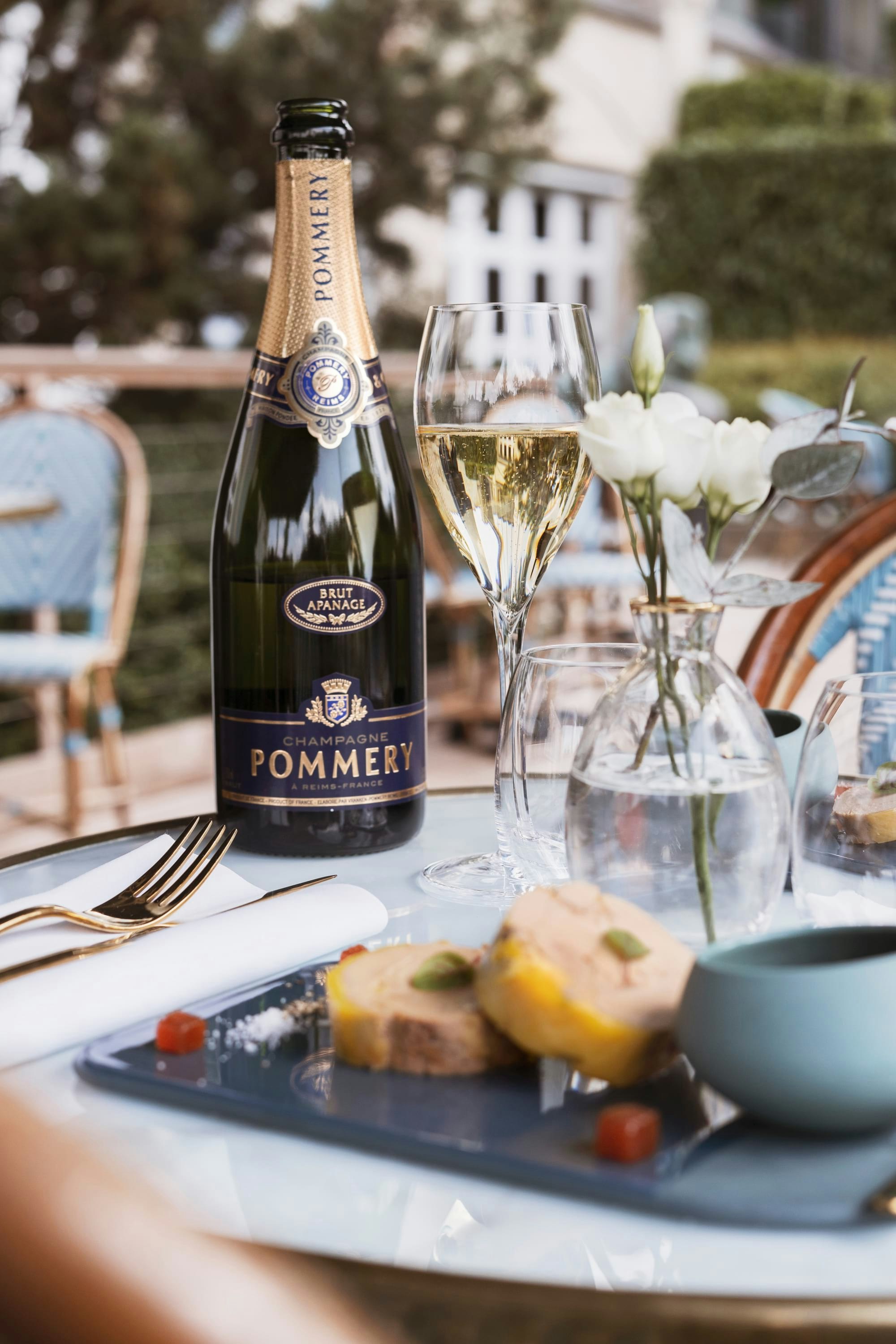 Bottle of Pommery Brut Apanage on table with glass and plate of foie gras