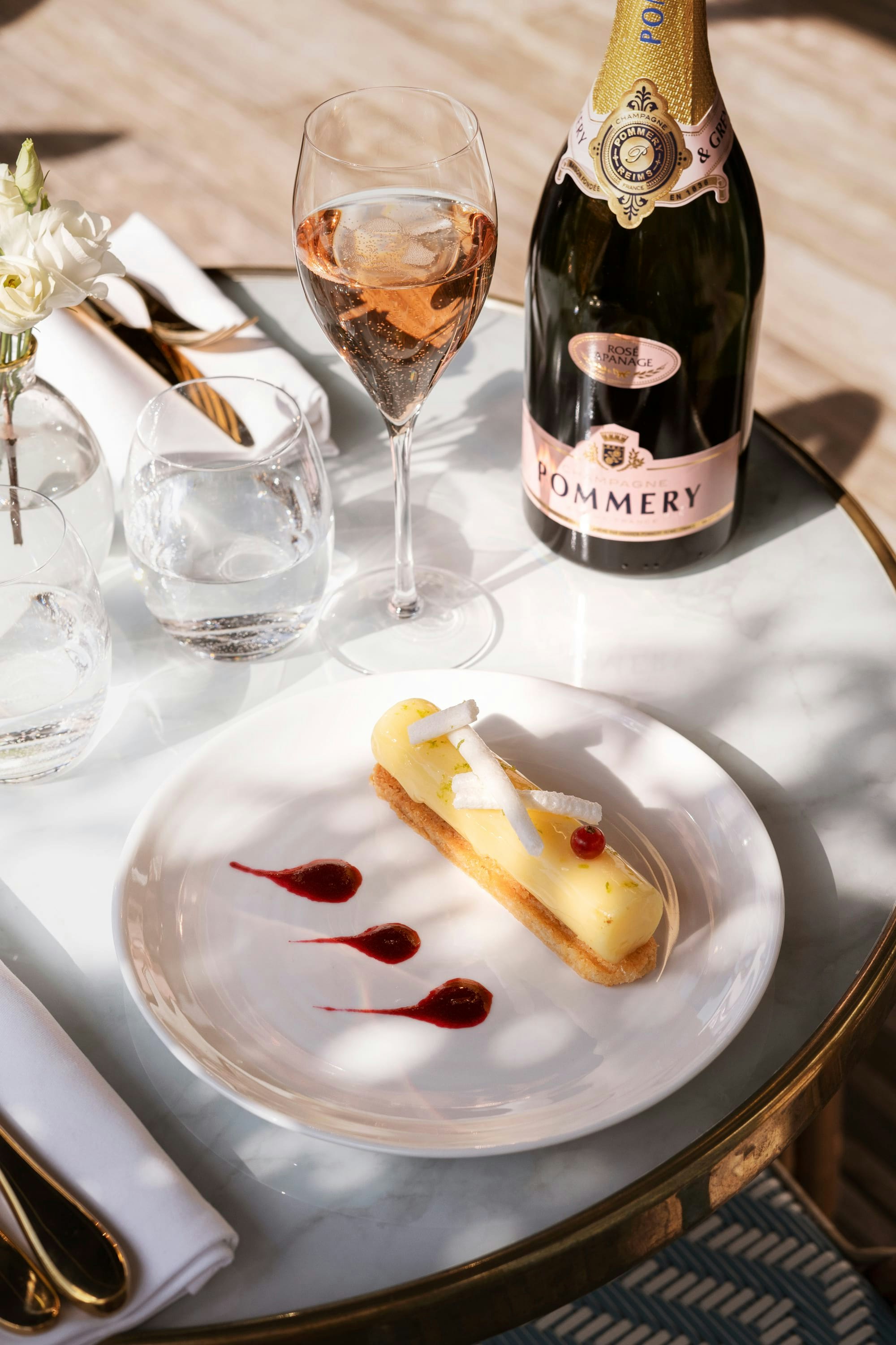 Une bouteille de Pommery Rosé Apanage avec une coupe ainsi qu'un dessert au citron