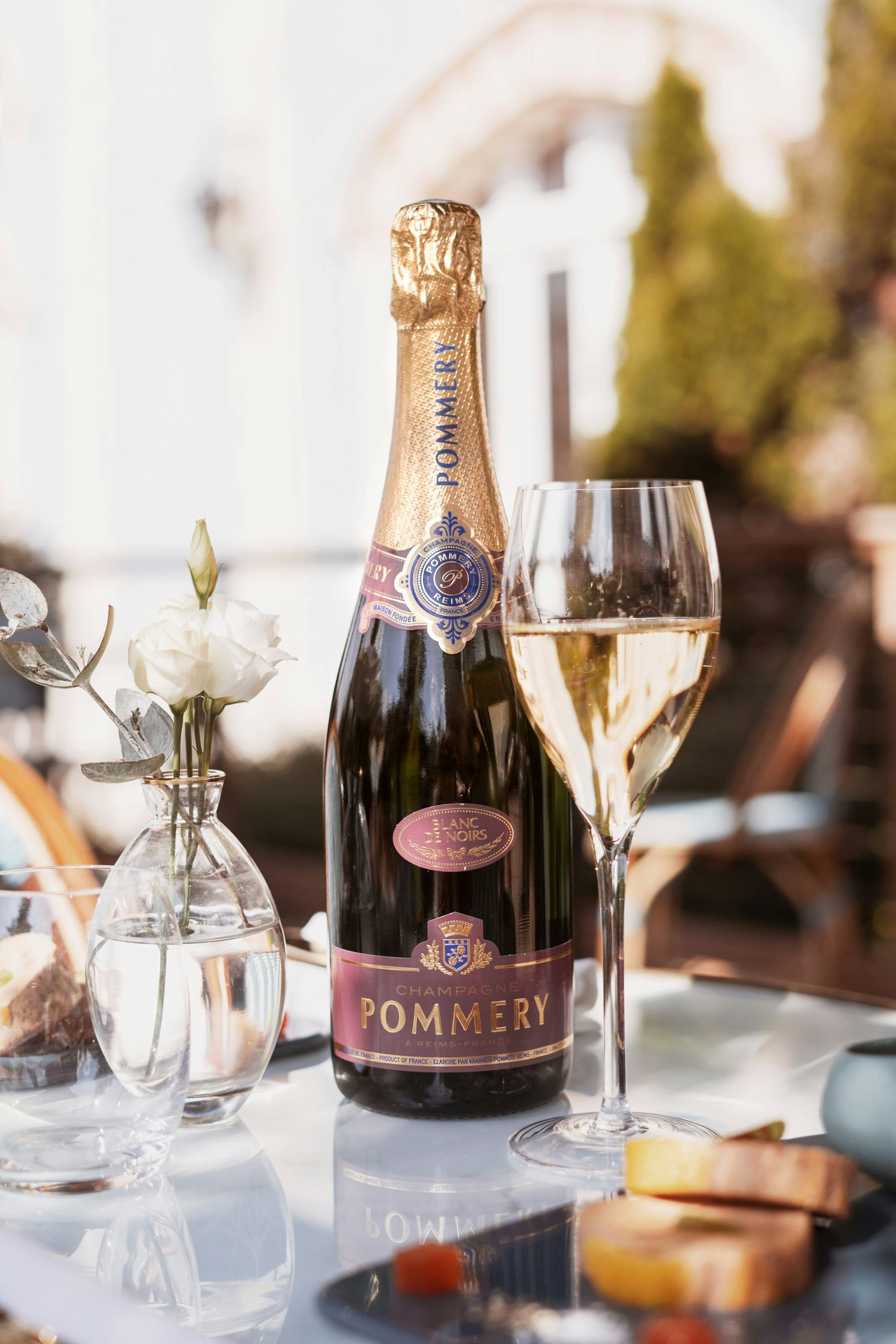 Une bouteille de Pommery Apanage Blanc de Noirs avec une coupe ainsi qu'une bouteille de foie gras