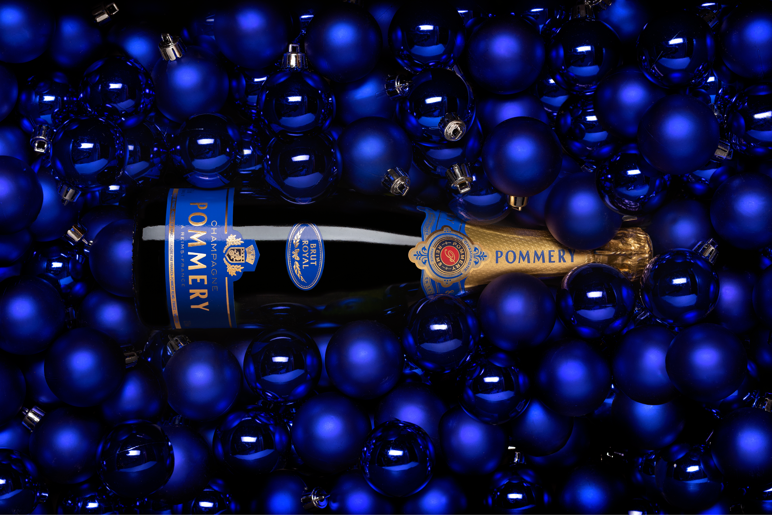 Une bouteille de Pommery brut royal 75cl couchée dans des boules de noel