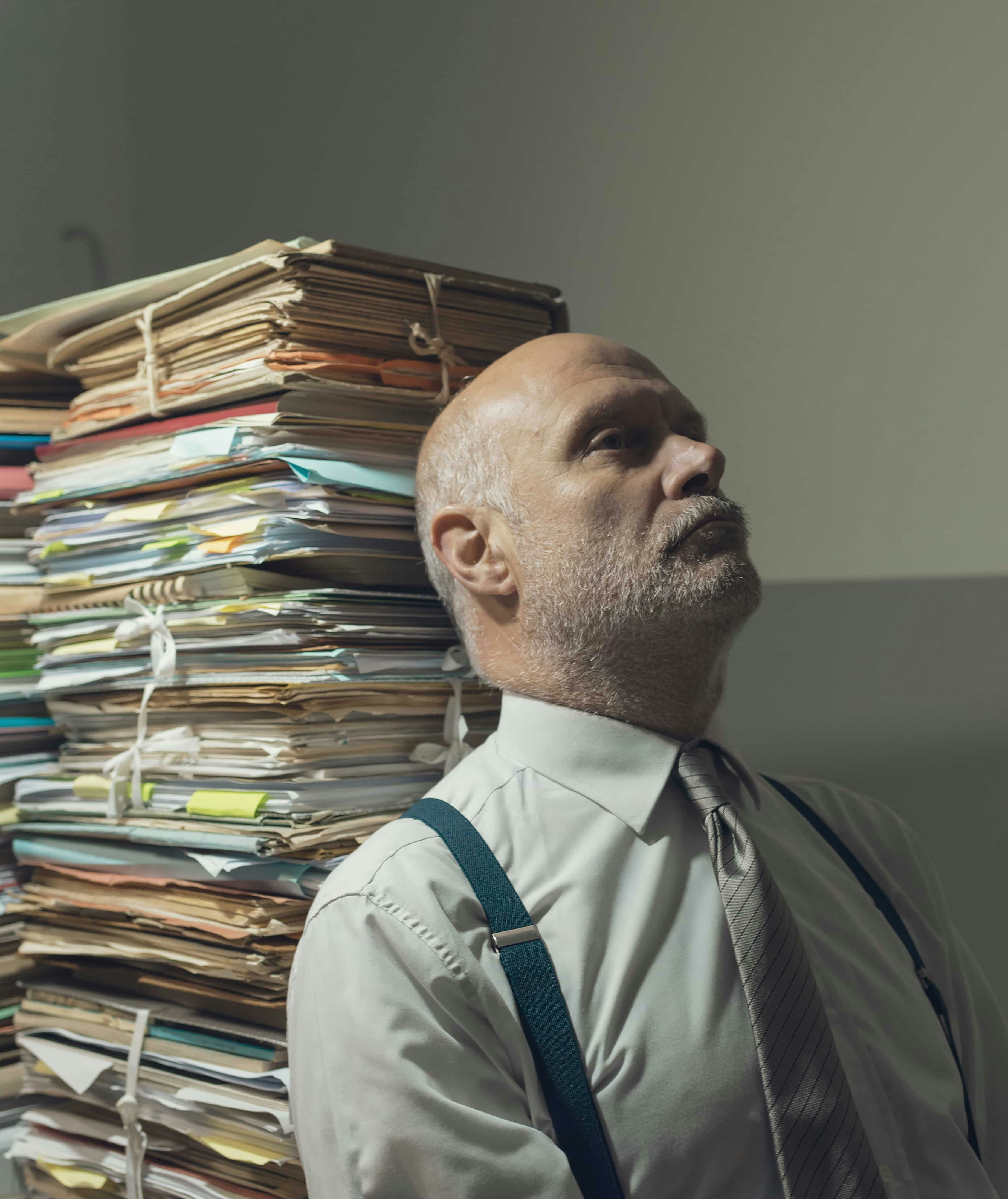 From old system to digital tools Businessman overwhelmed by the amount of paperwork he needs to do before leaving home.