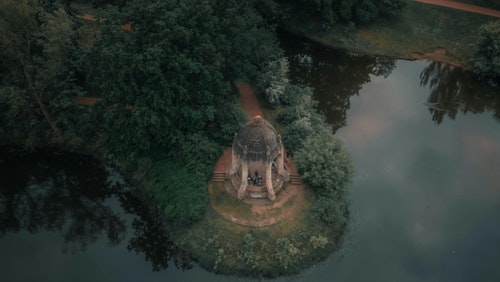 Ein Blick aus der Vogelperspektive auf einen von Wald umgebenen Pavillon in der Nähe eines Sees in Magdeburg. Ruhige und malerische Landschaft.