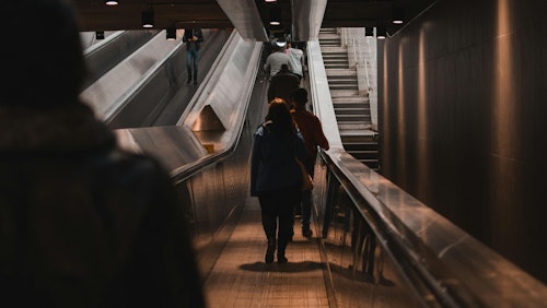 Menschen, die eine Rolltreppe in einer schwach beleuchteten Pariser U-Bahn-Station benutzen.