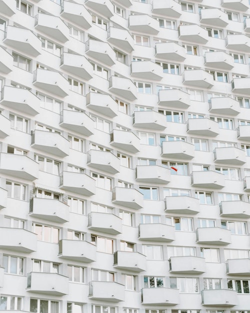 Ein beeindruckender Blick auf ein weißes Wohnhaus in Warschau mit seinen sich wiederholenden Balkonen und Fenstern.