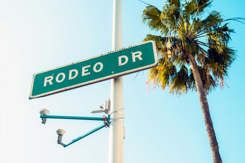 Ikonisches Rodeo Drive-Straßenschild mit einer Palme unter dem sonnigen Himmel von Beverly Hills.
