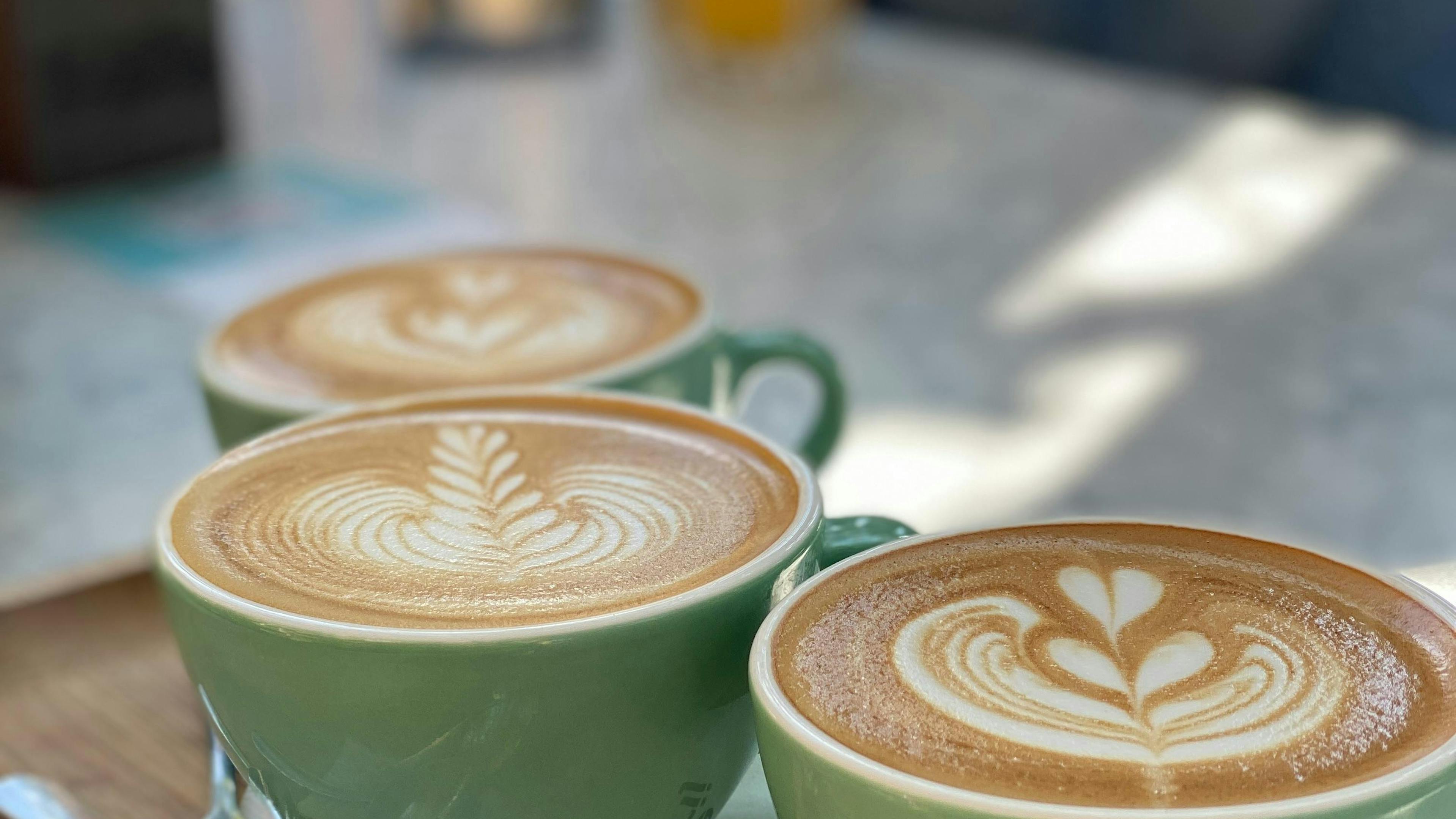 Genießen Sie drei wunderschön zubereitete Latte Macchiatos mit aufwendiger Latte Art in einem Amsterdamer Café.