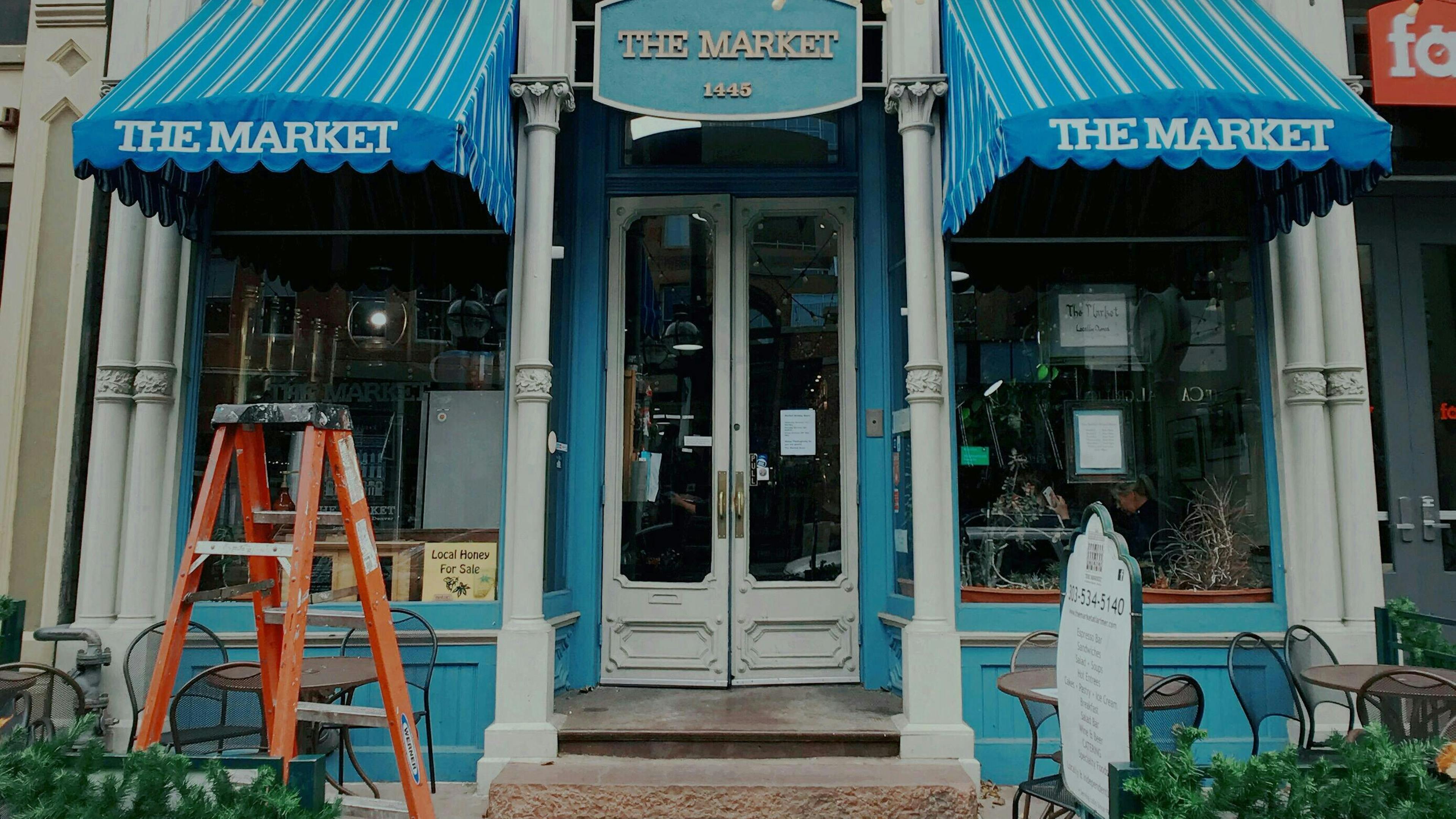 Bunte Schaufensterfront von „The Market“ am Larimer Square in Denver mit leuchtend blauen Markisen.