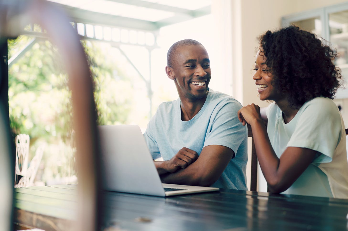 smiling couple sitting at a table with a laptop computer