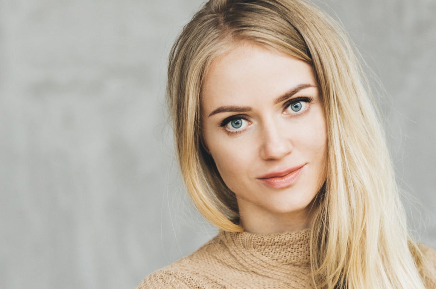 blond woman with blue eyes and a turtle neck sweater posing for a picture