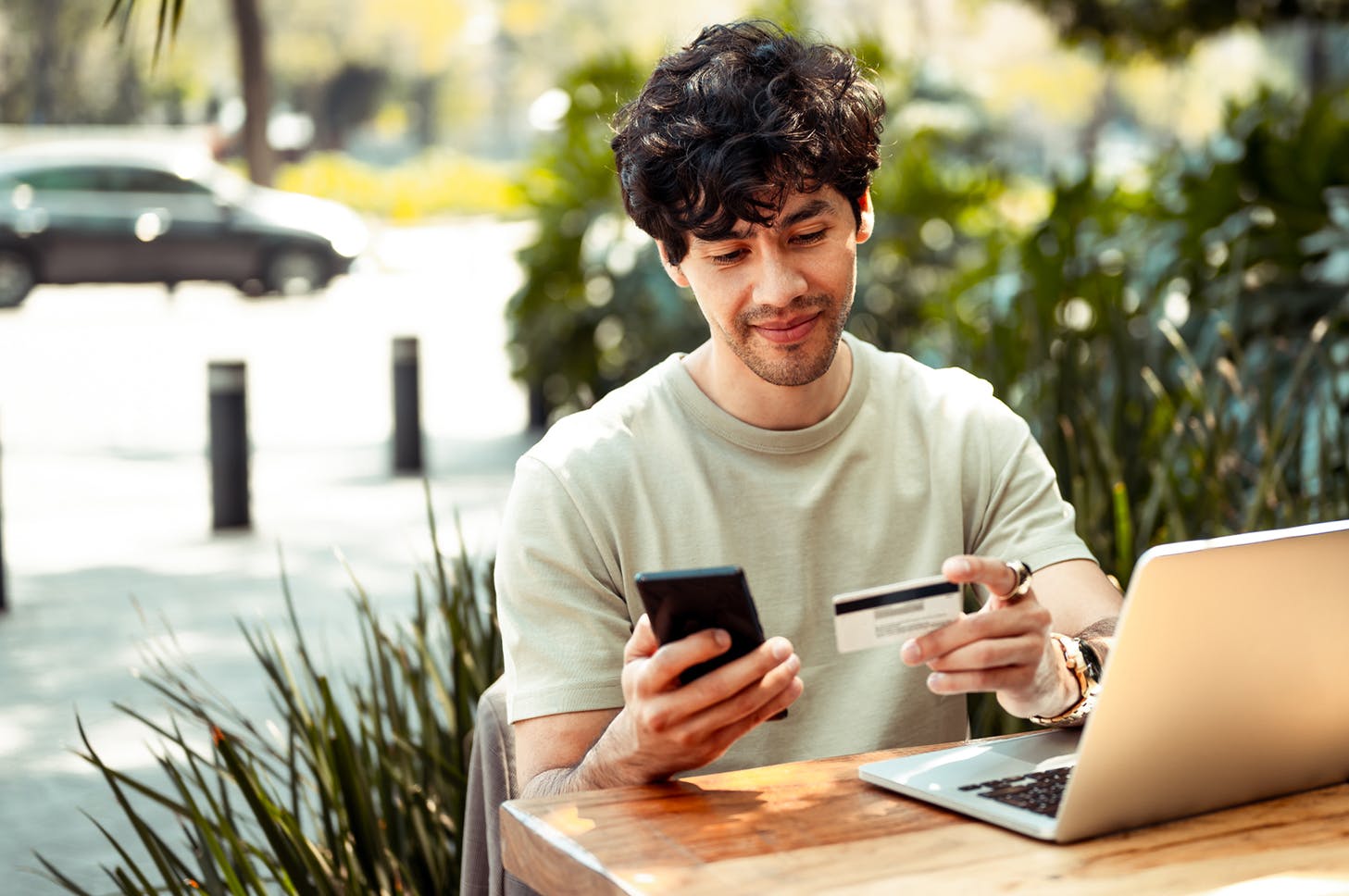 a man sitting at a table with a laptop and a credit card