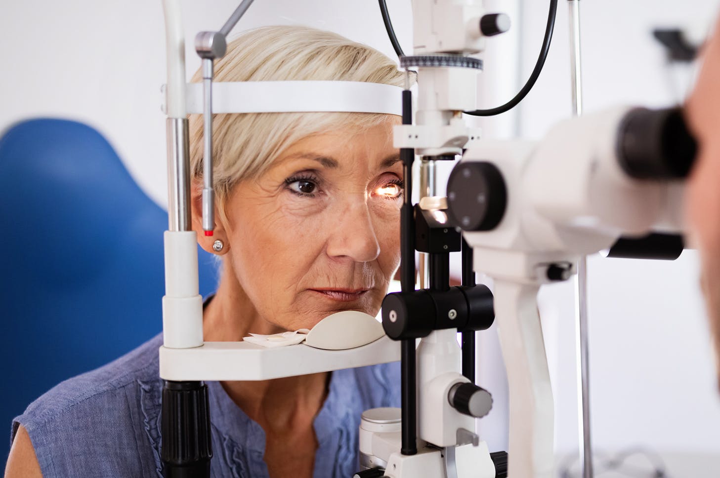 Older woman receiving eye exam with doctor in background
