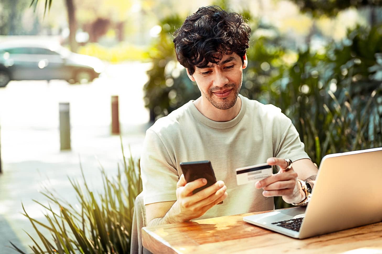Man looking at phone and credit card with laptop in front of him