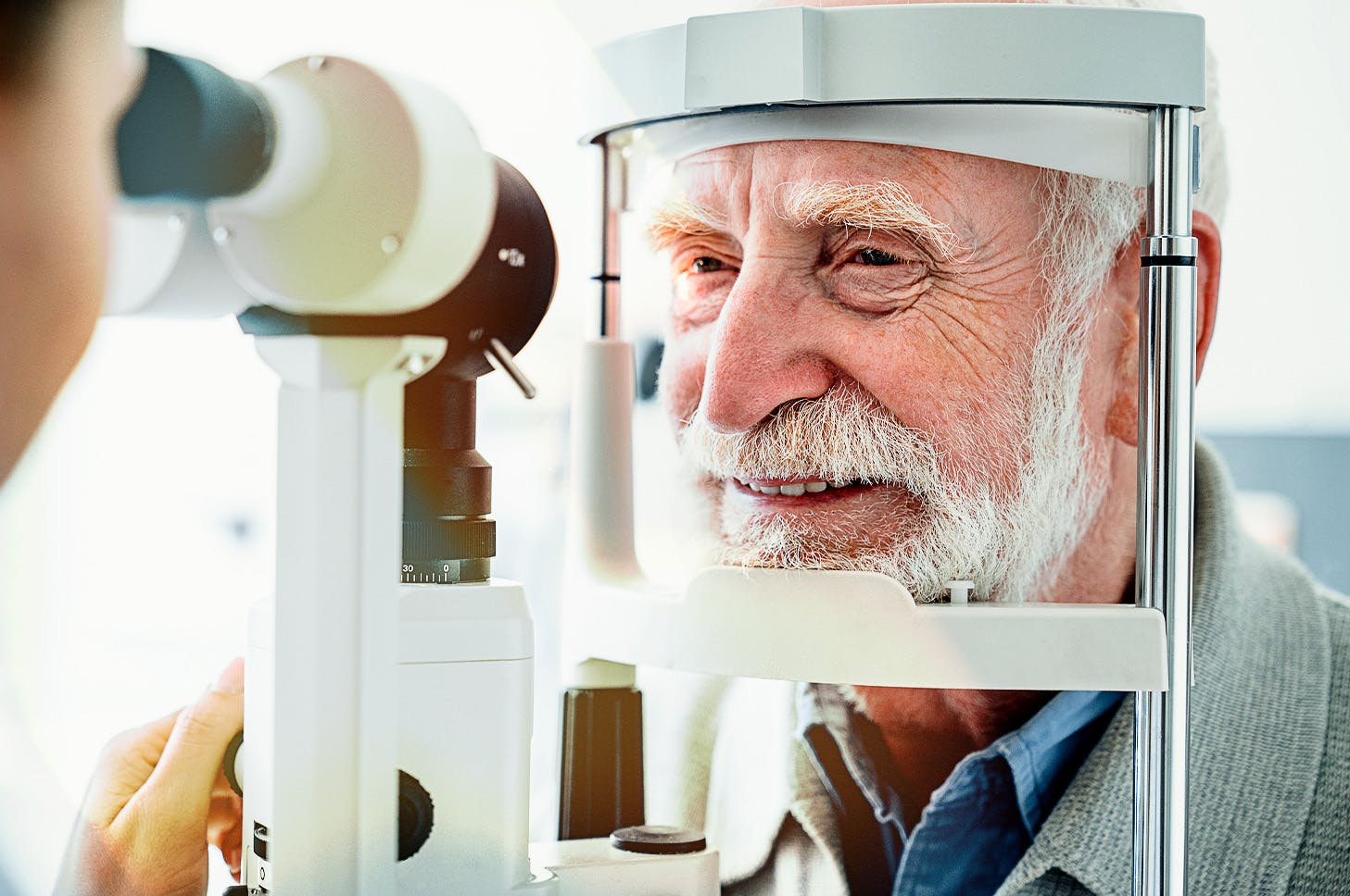 older gentleman getting resting his head on an eye exam machine