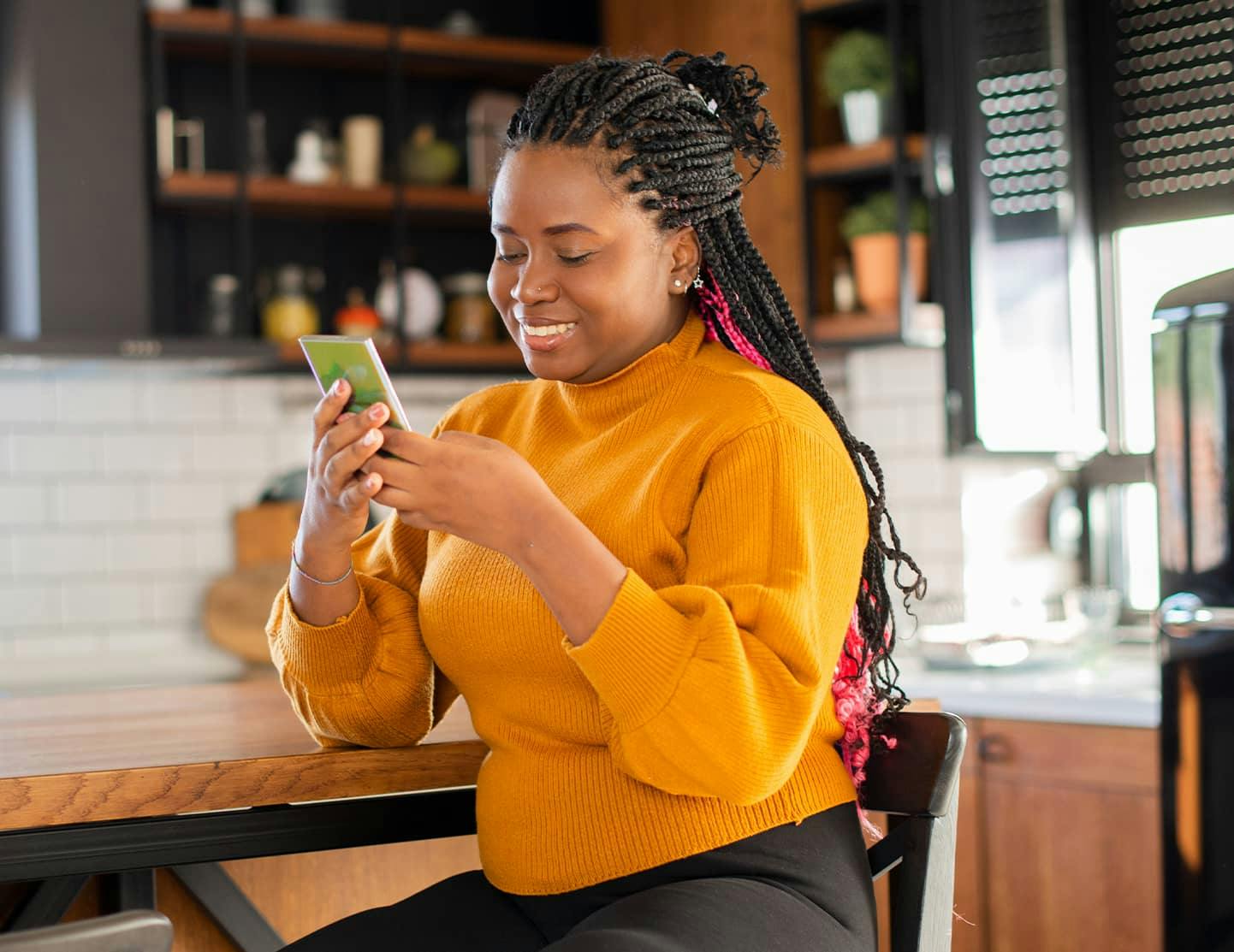 smiling woman sitting at a table using a cell phone