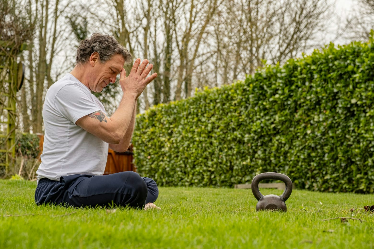 An instructor sat on the grass with a kettle bell