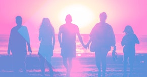 A family walking at the beach at sunset
