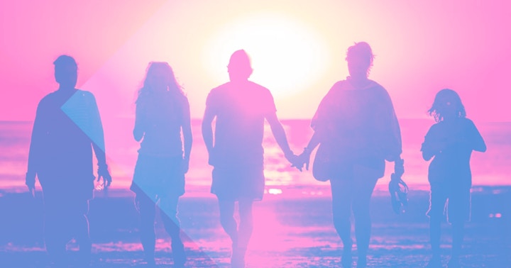 A family walking at the beach at sunset