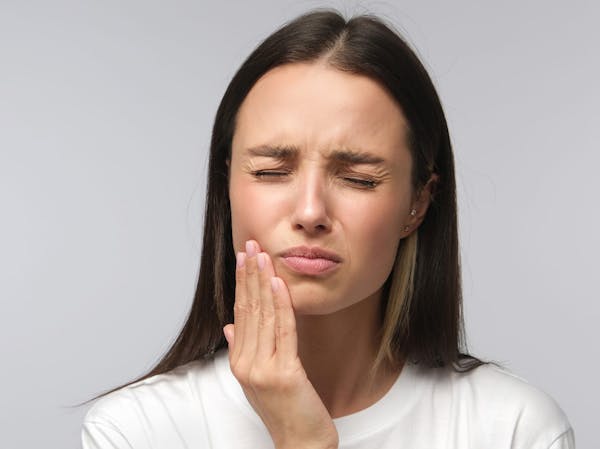 Woman with brown hair wincing at pain from TMJ disorder in Jacksonville