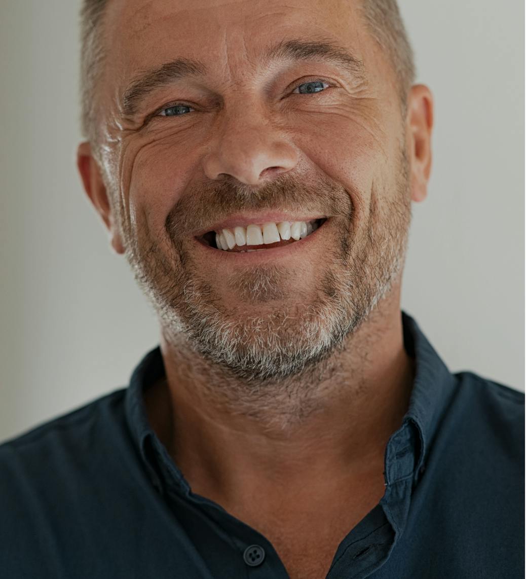 Older man with salt and pepper hair and beard, smiling