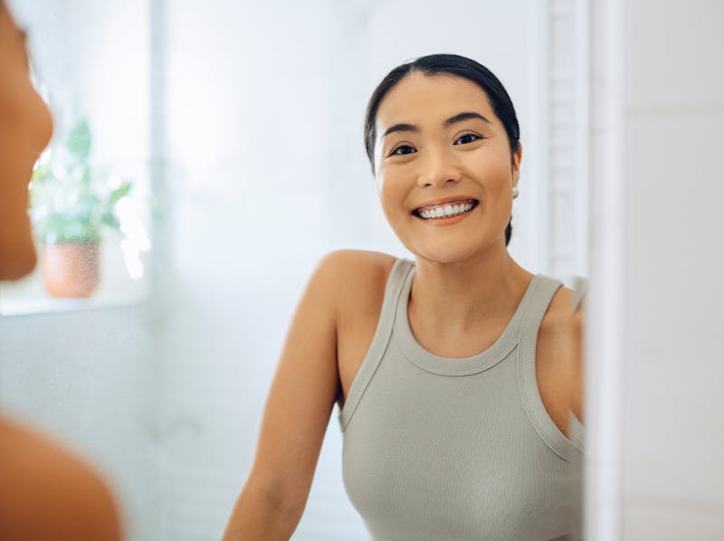 woman smiling into mirror