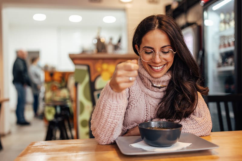 woman sipping soup in cafe