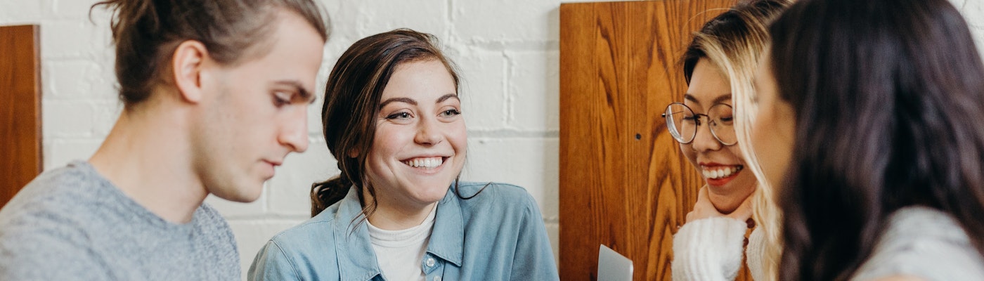 Op de afbeelding werken vier studenten samen aan een project