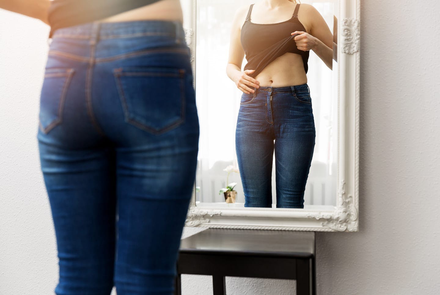 woman looking at torso in mirror