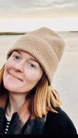 Headshot of Charlie Wileman, smiling on the beach in a beanie