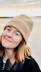 Headshot of Charlie Wileman, smiling on the beach in a beanie