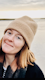 Headshot of Charlie Wileman, smiling on the beach in a beanie