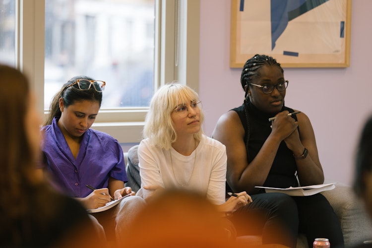 Three hackathon judges listening carefully and taking notes